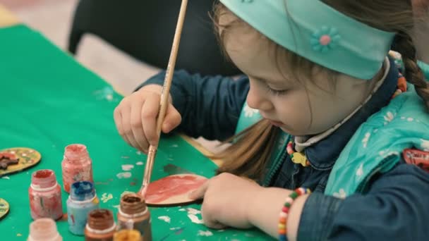 Little, cute girl paints the wooden figure — Stock Video