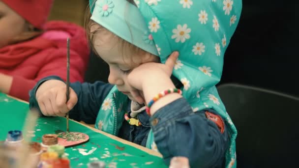 Μικρό, χαριτωμένο κορίτσι χρωματίζει την ξύλινη φιγούρα — Αρχείο Βίντεο