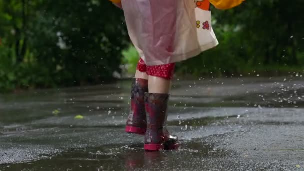 Niño en botas de lluvia saltando caóticamente en charco — Vídeos de Stock