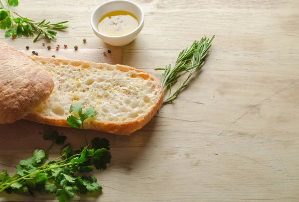 Ciabatta ekmeği otlar ile bir rustik ahşap tahta üzerinde ikiye böldüm