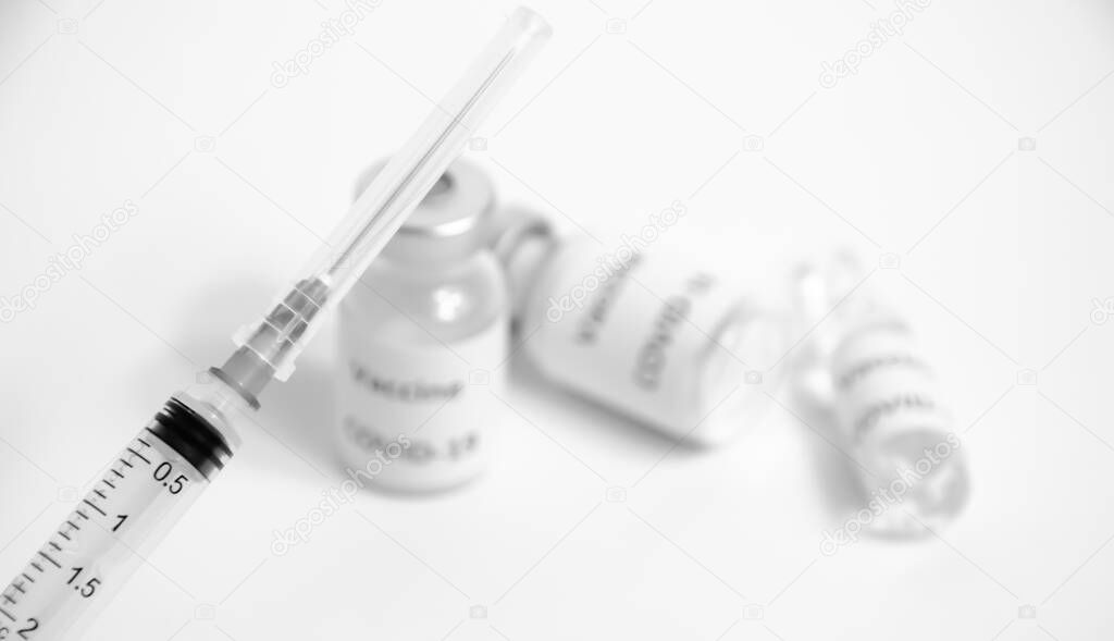 Selective focus on syringe on blurred background of ampoules with vaccine COVID-19. Health protection. Black and white Coronavirus Vaccine with copy space. Vaccination against Sars-CoV-2. Pandemic concept.