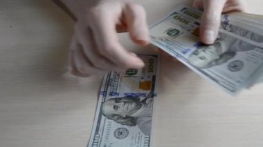 Yakından 100 Amerikan Doları 'nı sayıyorum. Para ödeme konsepti. Adam masaya dolar banknotları koyuyor. Amerikan Doları banknotları yakın planda hareket halinde. Tasarruf ve ipotek kavramı.