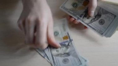 Yakından 100 Amerikan Doları 'nı sayıyorum. Para ödeme konsepti. Adam masaya dolar banknotları koyuyor. Amerikan Doları banknotları yakın planda hareket halinde. Tasarruf ve ipotek kavramı.