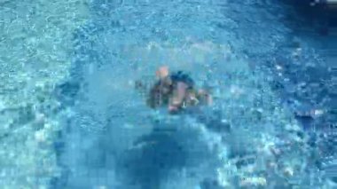 Beyaz adam mavi suyla havuzda yüzüyor. Yetişkin erkek yüzme havuzunda yüzer. Yaz tatili kavramı.