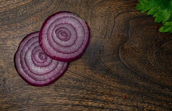 Onion slices on a wooden cutting board.