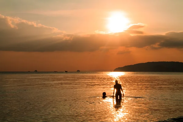 Silhuetas nos raios do sol poente — Fotografia de Stock