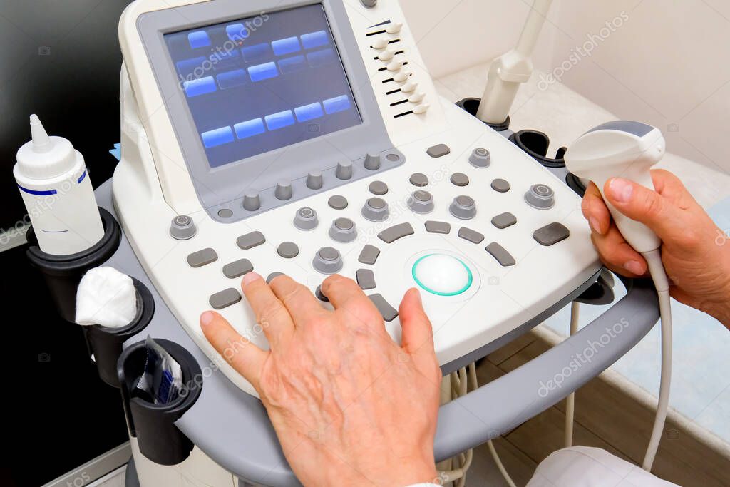 Control panel for ultrasound machine. The hands of an elderly doctor are visible
