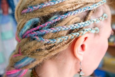 Kızın kafasında renkli örgü ve örgüler var. Yan görünüm, görünmeyen yüz.