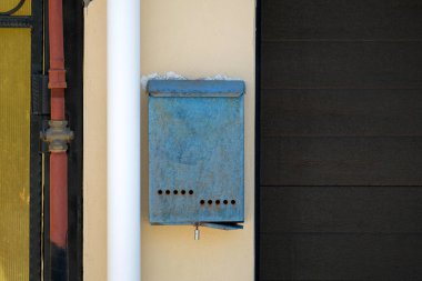 Boruyla kapı arasındaki duvarda eski bir posta kutusu asılı. Kimse.