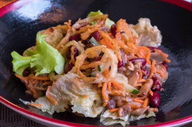 Siyah tabakta Asya salatası. Kırmızı fasulye, et, diğer malzemeler.