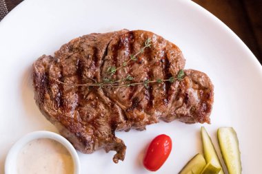 Tepesinde beyaz bir tabak biftek. Bulanık arkaplan, insan yok.