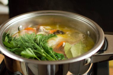 Çorbaya otlar, defne yaprakları ve baharatlar ekliyorum. Sebzeli su ve et bir tencerede kaynıyor..