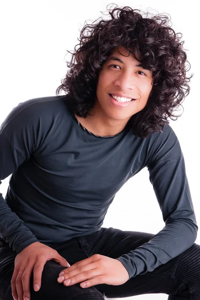 Jovem bonito com cabelo encaracolado e um sorriso amigável . Fotografia De Stock