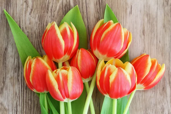 Tulipes rouges et jaunes sur la surface en bois — Photo