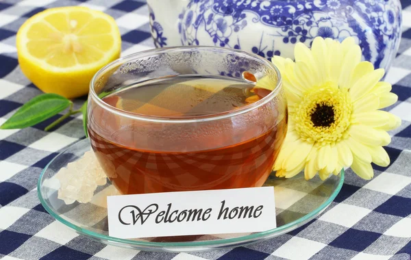 Tarjeta de bienvenida a casa con taza de té, limón, crema de gerberas — Foto de Stock