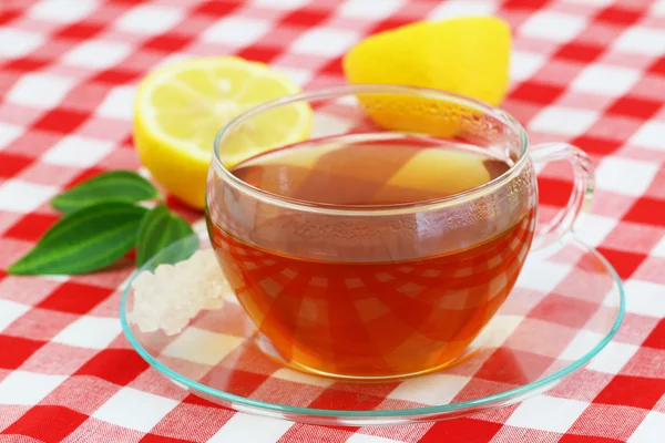 Cup of tea and lemon on checkered cloth — Stock Photo, Image