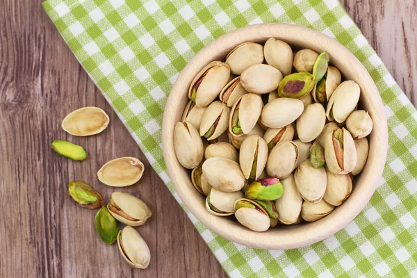 Nueces de pistacho en cuenco de madera sobre tela a cuadros — Foto de Stock