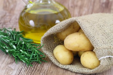 Yeni patates jüt çanta, taze biberiye ve zeytin yağı