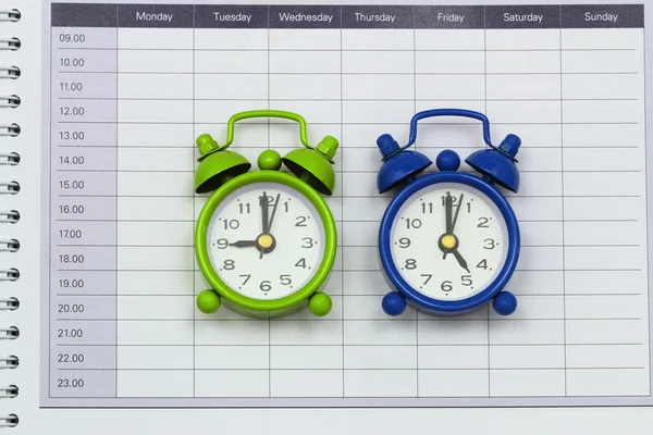 Two miniature clocks displaying time on open agenda — Stock Photo, Image