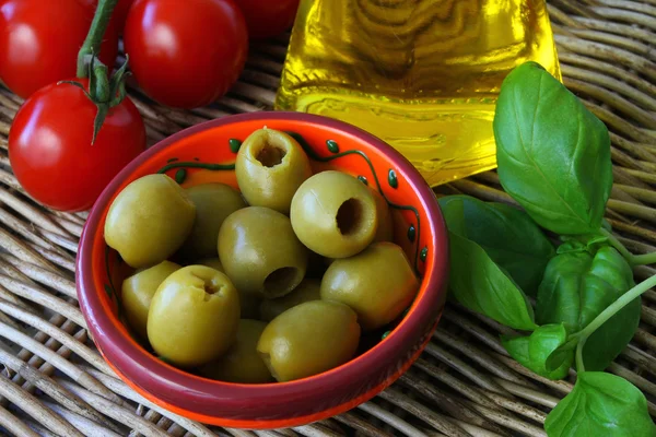 Olives vertes, huile d'olive, tomates cerises et feuilles de basilic frais — Photo