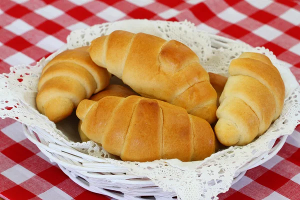 Butter croissants in bread basket on checkered tablecloth — Stock Photo, Image