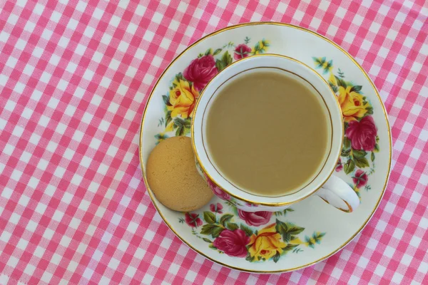 Чай в винтажной фарфоровой чашке на розовой и белой клетчатой ткани с копировальным пространством — стоковое фото