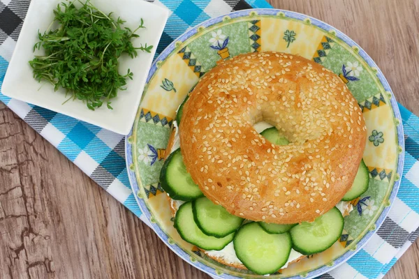 Bagel met roomkaas, komkommer en waterkers met groene salade — Stockfoto