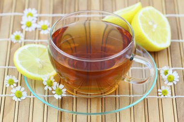 Bambu hasır üzerinde limon ve papatya çiçekli çay