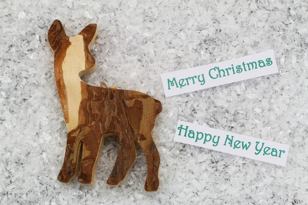 Merry Christmas and Happy New Year card with wooden roe deer, on snowy surface — Stock Photo, Image