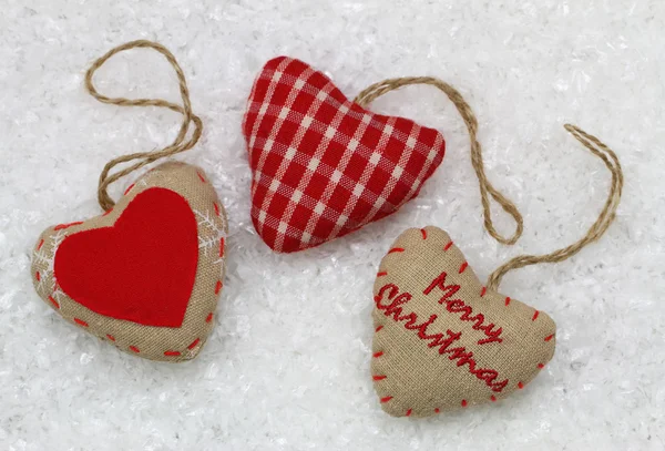 Merry Christmas card with three red hearts, on snowy surface — Stock Photo, Image