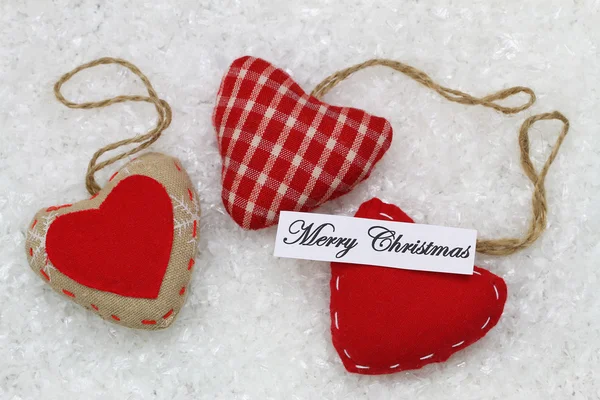 Merry Christmas card with three red hearts, on snowy surface — Stock Photo, Image