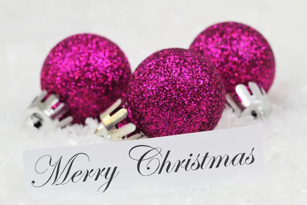 Feliz tarjeta de Navidad con bolas púrpuras, en la superficie nevada — Foto de Stock