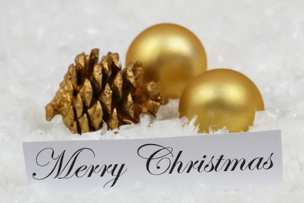Feliz cartão de Natal com bugigangas douradas, cones de pinho na superfície nevada — Fotografia de Stock