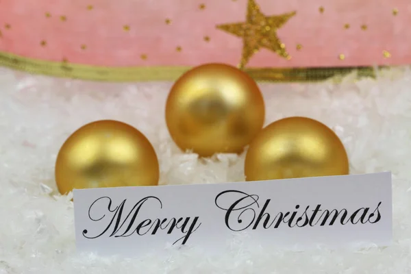 Feliz Navidad tarjeta con bolas de oro, cinta roja en la superficie nevada —  Fotos de Stock
