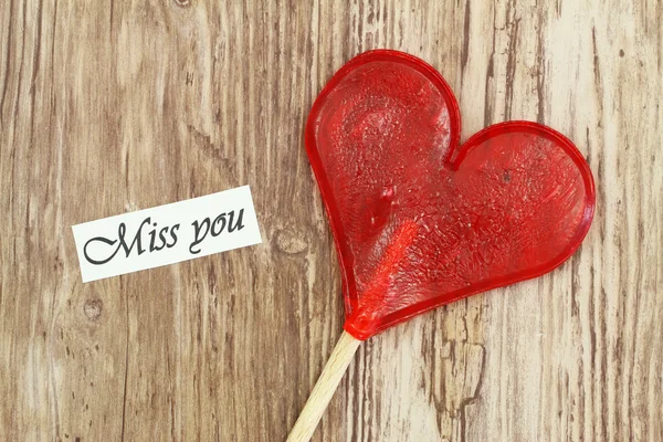 Miss you card with heart shaped lollipop on wooden surface — Stock Photo, Image