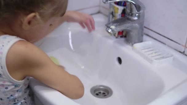 Ένα κορίτσι μπροστά στο νιπτήρα πλένει τα χέρια της με σαπούνι. — Αρχείο Βίντεο