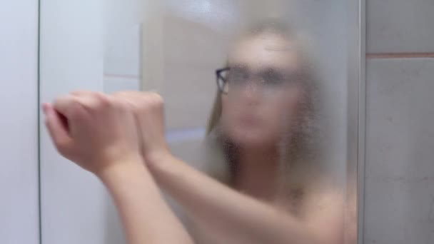 Жінка у ванній в окулярах протирає помилкове дзеркало рукою — стокове відео