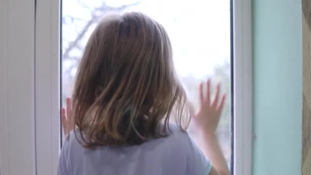 Девушка стоит перед окном и стучит по стеклу ладонью. — стоковое видео