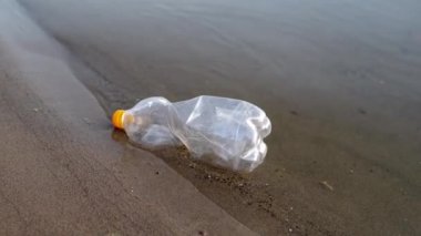 Bir gönüllü, bir bahçe aletini kullanarak bir nehirden ya da gölden plastik şişe çöpünü kaldırıyor. Çevre kirliliği