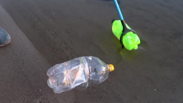 Ein Freiwilliger entfernt Plastikflaschenmüll aus einem Fluss oder See, indem er ein Gartenwerkzeug in Großaufnahme nimmt. Umweltverschmutzung — Stockvideo