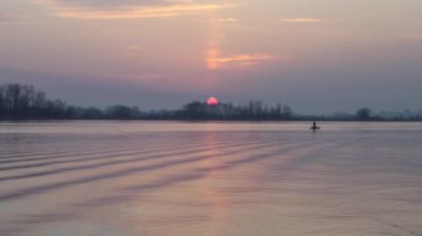 Nehrin üzerinde gün batımı kayboluyor, göl. Sudaki küçük dalgalar