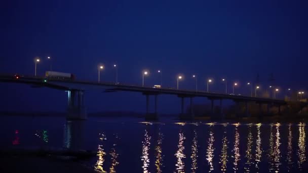 Russische Straßenbrücke über den Fluss. Die Nachtbrücke leuchtet mit Laternen und reflektiert den Glanz des Wassers — Stockvideo