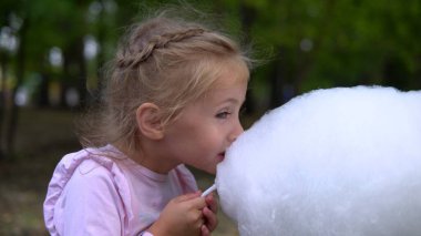 Dışarıda elinde pamuk tutan ve dışarıda yemek yiyen bir kız var.