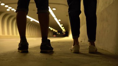 Bir çift gecenin ilerleyen saatlerinde yanan bir tünelde yürür.