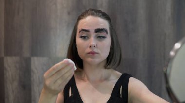 Pamuklu pedi olan bir kız siyah boyayı gözlük ile yıkar.