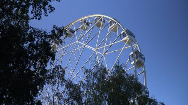 Parkta, büyük bir dönme dolap yavaşça dönüyor. Yüksek irtifa görünüm tekerleği 4k