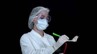 Hemşire ders kitabını alır ve siyah arka plan 4k üzerine kalemle yazar.