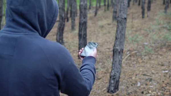 Человек Капюшоне Ходит Лесу Компасом Смартфоне — стоковое фото