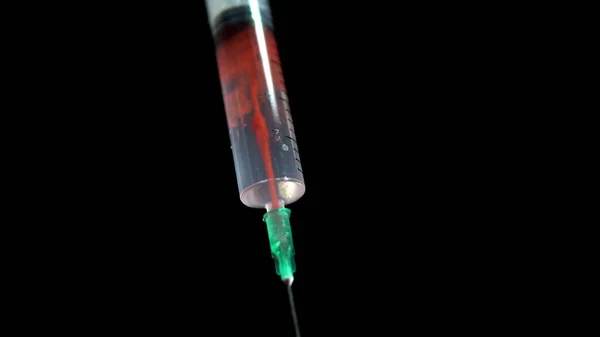 赤い液体は黒い背景に白い液体と注射器で混合されます4K — ストック写真