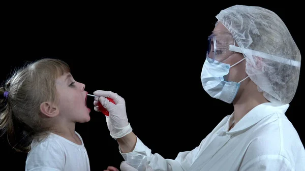 A nurse takes a covid-19 test from a girl. The child takes the analysis on a black background 4k